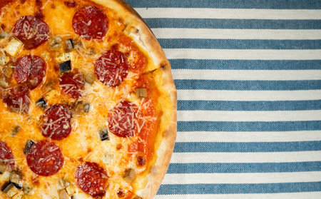 Delicious pizza with salami sausage, mozzarella cheese and parmesan on a wooden board in a pizzeria on a tablecloth. Banner.の写真素材