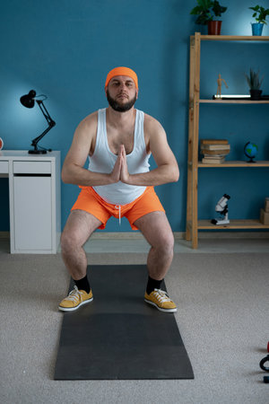 40s man doing squats and holds hands namaste at home. Yoga Pose Chair.の写真素材
