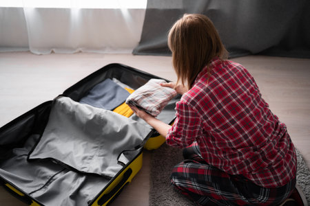 Mature woman packing suitcase on floor for new journey, preparing vacation. Travelingの写真素材