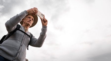 Senior traveler with smartphone photographing historic landmark outdoors