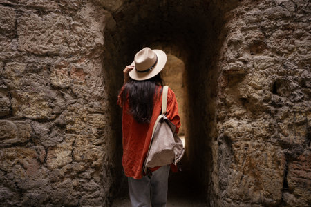 Traveler walking through ancient stone passage with backpackの写真素材