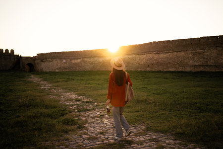 Tourist walking toward ancient fortress at sunsetの写真素材