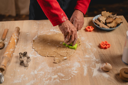 Christmas and New Year traditions concept. Christmas bakery in the kitchen. Man making gingerbread, cutting cookies of gingerbreads dough. Cooking process and family culinaryの写真素材