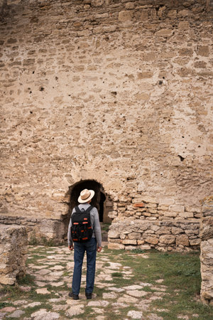 Retired man exploring ancient fortress, taking in historical landmarks during peaceful visit, enjoying journey through heritage site on calm autumn day.の写真素材