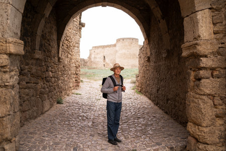 Retired traveler visits ancient fortress, soaking in historical grandeur and enjoying tranquil surroundings of ancient ruins during a peaceful autumn journeyの写真素材