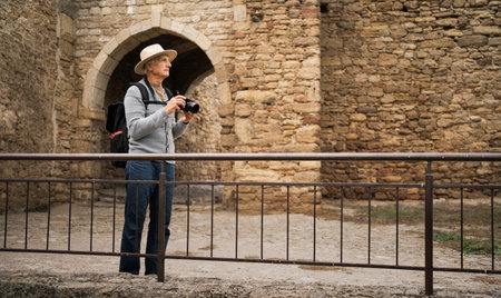 A retired male tourist takes photos while walking in an ancient fortressの写真素材