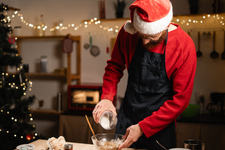 Man in Santa hat mixing Christmas cookie doughの写真素材