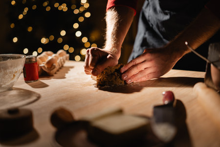 Man making gingerbread cookies kneading dough cooking in kitchen decorated for Christmas, close up.の写真素材