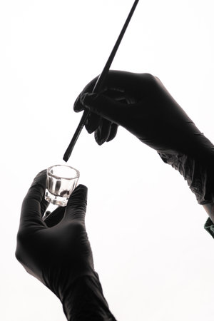 Hands of beautician holding eyebrow tint brush and glass containerの写真素材