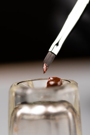 brush with paint into a glass cup for mixing eyebrow paint