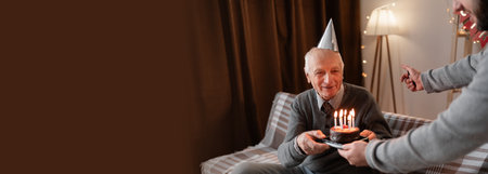 Close-up of mature man holding cake with Birthday candles while celebrating anniversary with his sonの写真素材