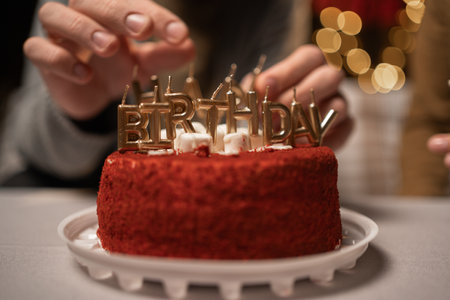 Happy birthday cake red velvet decorated with gold candles on the blurred lights backgroundの写真素材