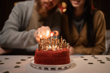 Man lighting happy birthday candles burning on a cake. Close-up.の写真素材
