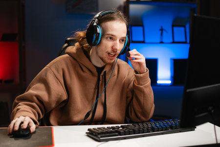 Streamer gamer playing online video games uses microphone to broadcast live at night at home in his spare timeの写真素材