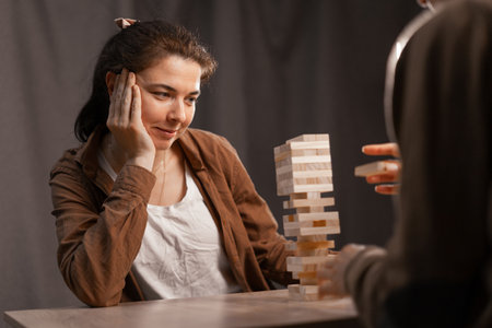 Two woman relationship concept. Female friends playing board game builds wooden block tower.の写真素材