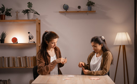 Female couple playing cards together in living roomの写真素材