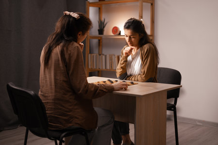 Two women are playing a checkers game at home. Leisure and weekendの写真素材