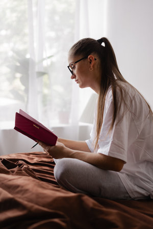 Woman writing notes in notebook while sittingの写真素材