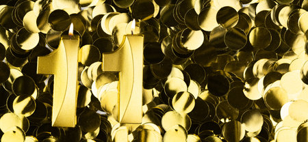 Golden number eleven candle on shiny yellow confetti background. Festive backdrop for eleventh...