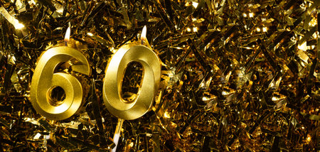 Golden candles number 60 on gold tinsel background. Celebration sixtieth birthday. Concept of celebrating birthday and anniversary.の写真素材