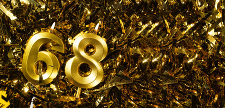 Golden candles number 68 on gold tinsel background. Celebration sixty-eighth birthday. Concept of celebrating birthday.の写真素材