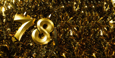 Golden candles number 78 on gold tinsel background. Celebration seventy-eighth birthday. Concept of celebrating birthdayの写真素材