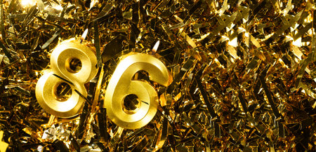 Golden candles number 86 on gold tinsel background. Celebration eighty-sixth birthday. Concept of celebrating birthdayの写真素材