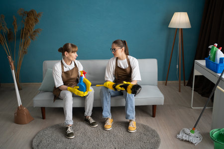 Female cleaners in uniform taking break and talking during house cleaningの写真素材