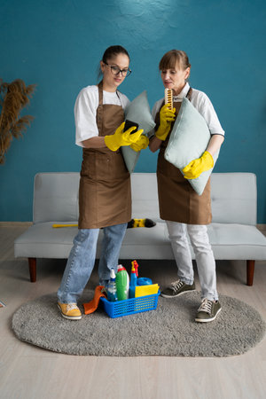 Two female colleagues of a cleaning service are chatting, relaxing after work, reading a message or social networks using a smartphoneの写真素材