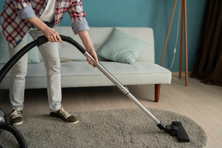 Woman cleans carpet with vacuum cleaner. Janitor vacuuming carpet. Home routine concept.の写真素材