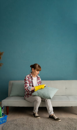 Woman cleaning couch and pillow in her apartment.の写真素材