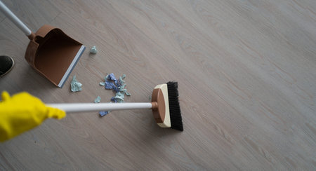 Cleaning the house. Sweeping the floor with a broom and dustpan, top view
