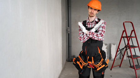 Young construction worker or builder man wearing blue overalls showing rejection expression crossing arms with angry faceの写真素材