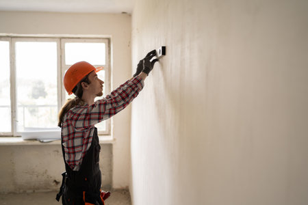 Builder or Construction worker in protective hardhat checking level of wall. Measurementの写真素材