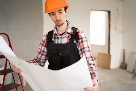 Builder wearing orange helmet reading house blueprints