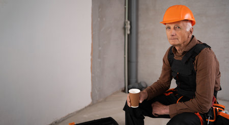 Builder with Coffee. Elderly engineer or construction worker relax on break at construction siteの写真素材