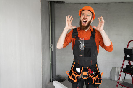 annoyed angry builder or architect in furious gesture with his hands in repair house process....