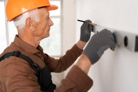 Builder with spirit level measure wall for maintenance, home repair. Construction handymanの写真素材