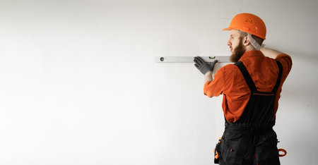 Builder wearing hardhat using spirit level measuring wall. repair, building and homeの写真素材