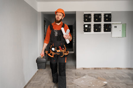 Handyman in Helmet Holding Toolbox While Standing in Corridor During Home Repair Work