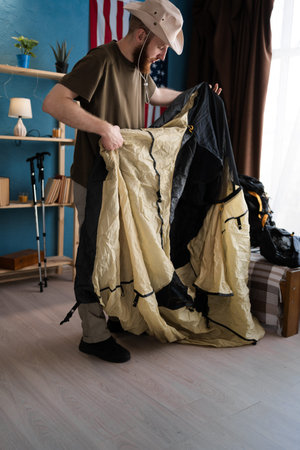 bearded man traveler preparing for hiking trip unpacking tent checking completeness. Hiking and...