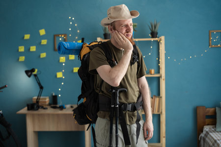 Young bearded man traveler prepare for hiking vacation at home suffering from teeth ache. healthy, medicine and travelの写真素材