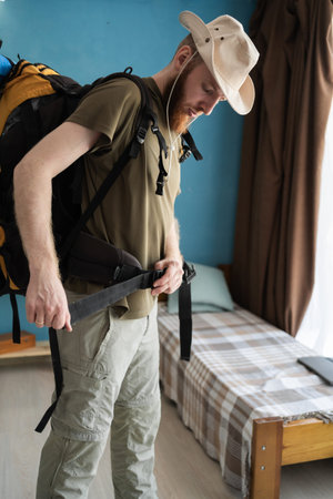 Young bearded man traveler preparing for hiking big backpack at home. backpacker travel concept