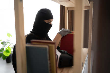 Burglar, robber or thief breaks home. Woman wearing black balaclava stealing things searching money...