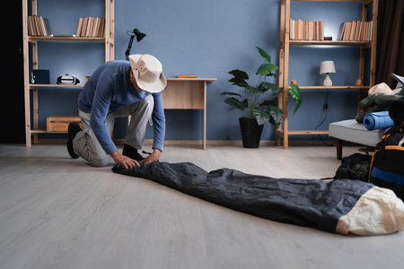 senior male hiker packing sleeping bag indoorsの写真素材