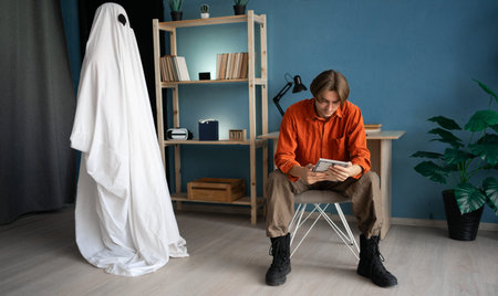 Sad widower looking at old photo of his woman, ghost wife standing nearby. Concept of life, death and afterlifeの写真素材