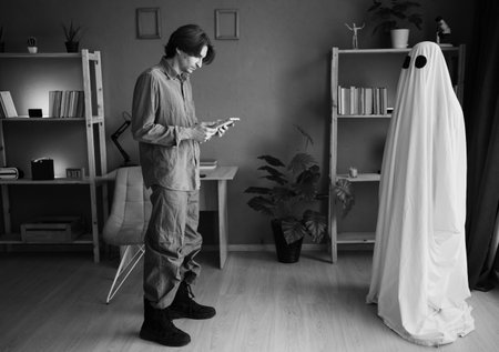 Lonely widower stares at picture of lost wife while ghost of woman watches him from nearby. Afterlife and memory scene filled with silence and pain.の写真素材
