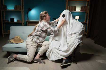 happy friends in costumes preparing for Halloween party sitting on sofa at homeの写真素材