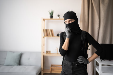 Thoughtful young woman wearing black balaclava and gloves.の写真素材