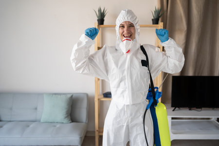 Young female exterminator or contractor doing pest control at home showing victory gestureの写真素材